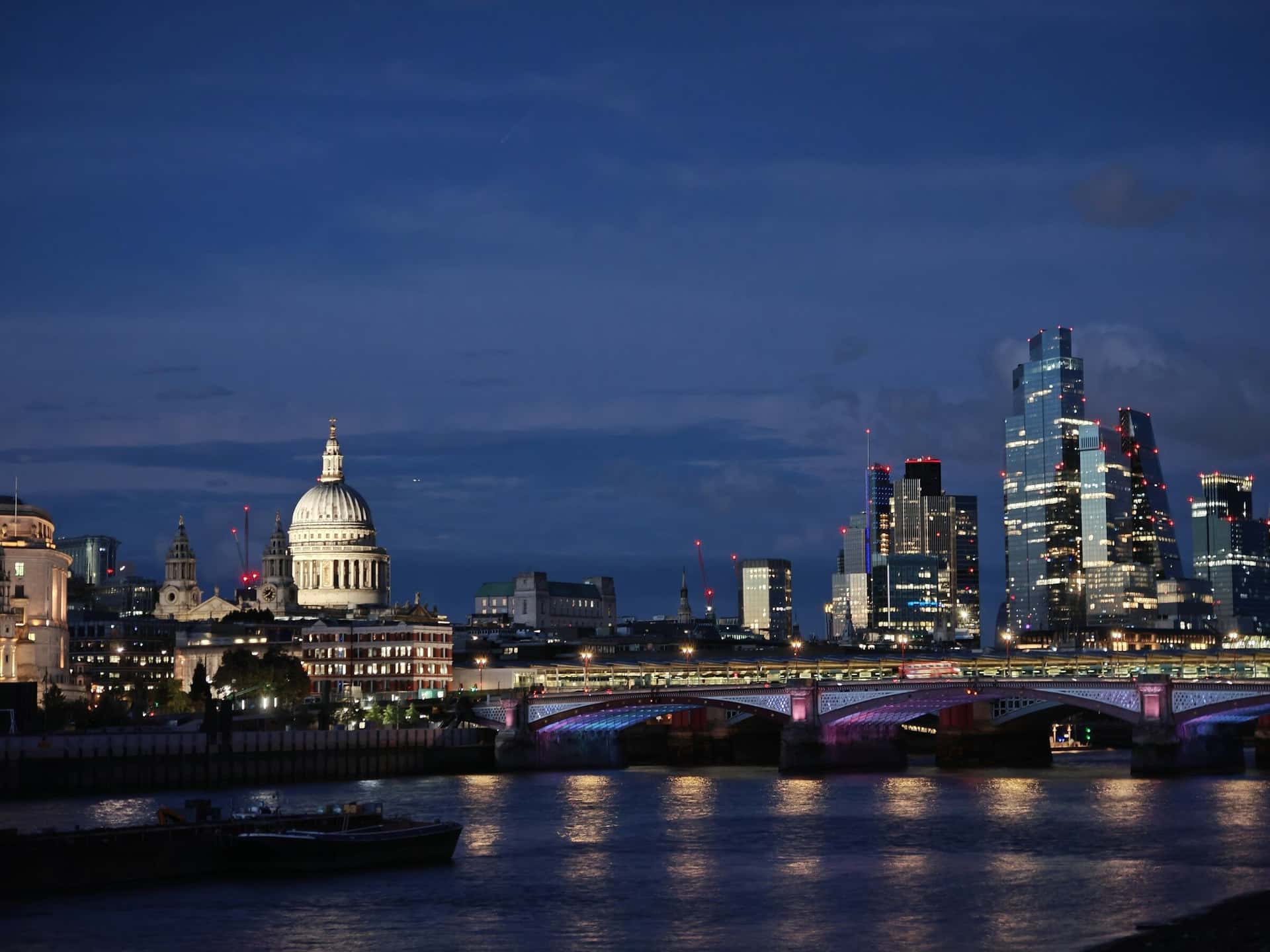 St Paul's Cathedral and the towers of the City of London across the Thames at dusk.