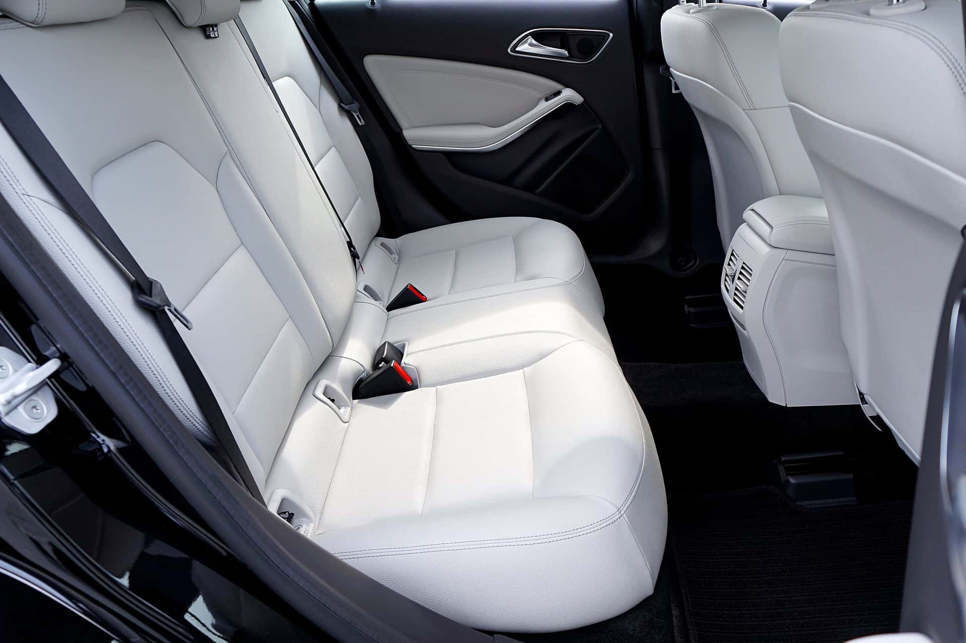 The rear seats of an executive saloon in pale leather, the door open on an empty cabin.