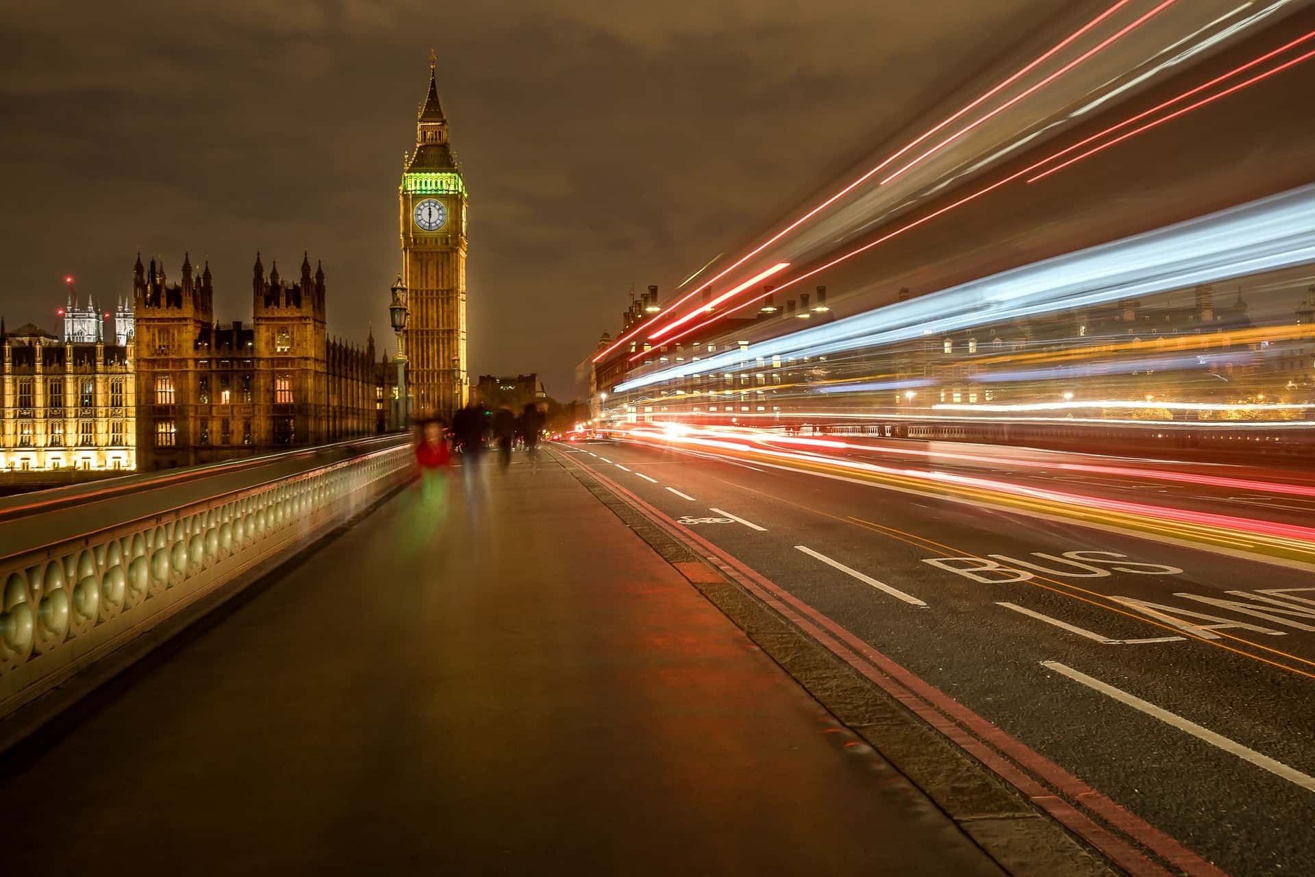 Westminster Bridge at night, the lights of passing traffic drawn into long streaks beside the Elizabeth Tower.